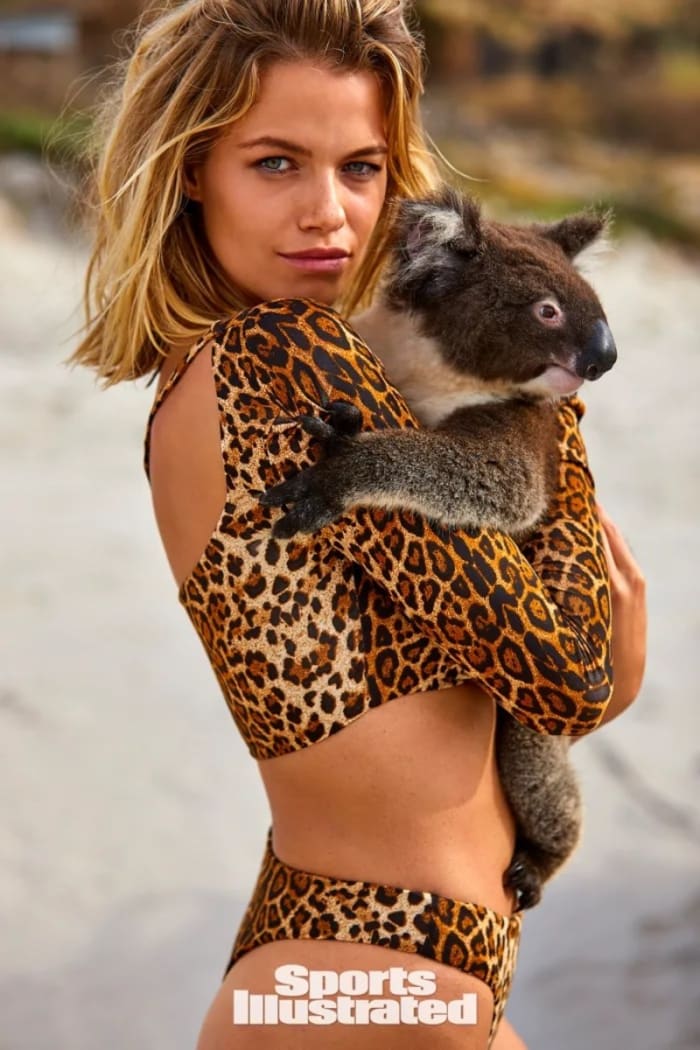Hailey Clauson poses with a koala in a leopard-printed long sleeve swimsuit top and matching bottoms.